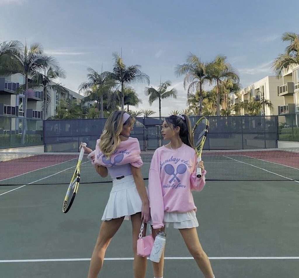 Rosa tennisracket och tillhörande utrustning fotograferad på tennisbana